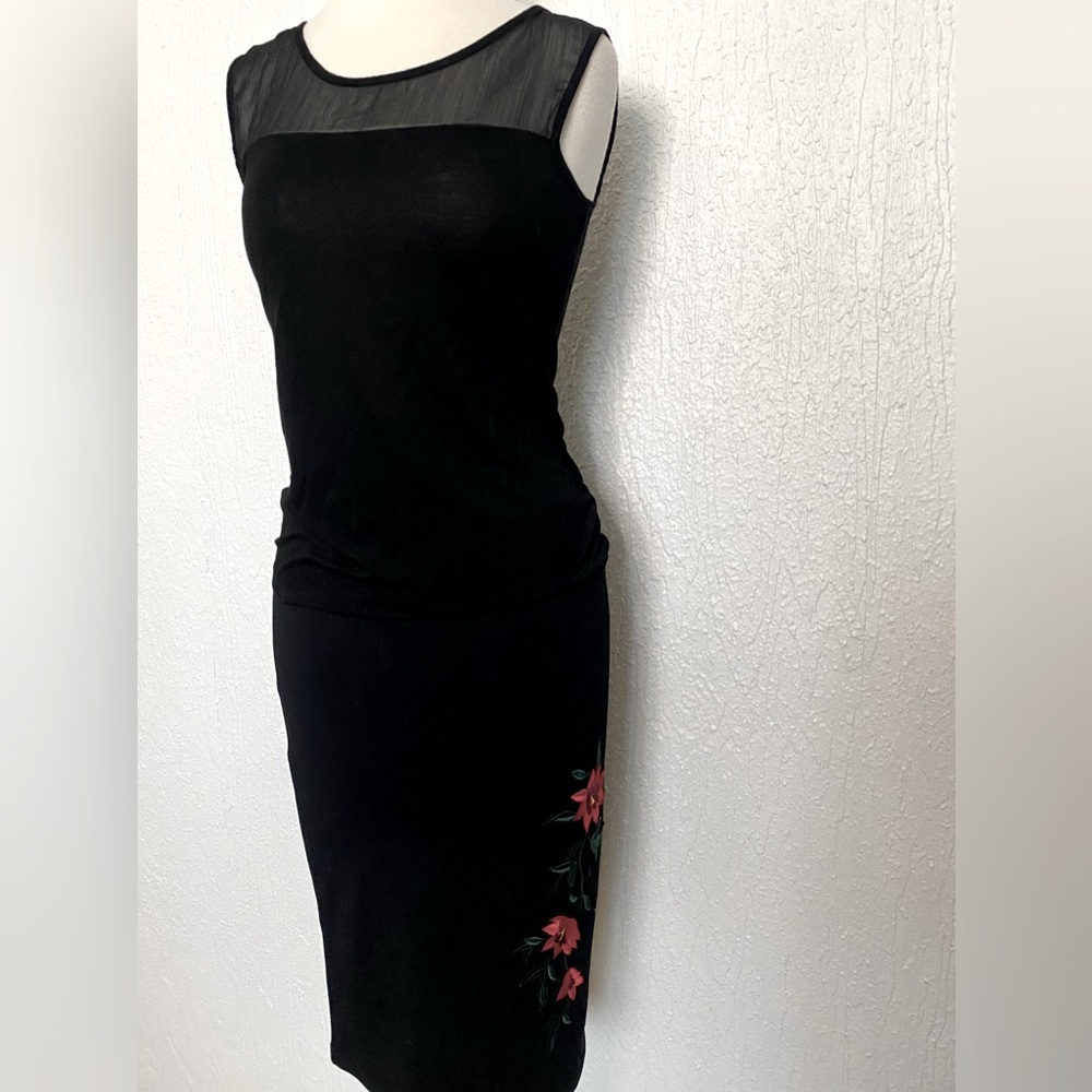 Black sleeveless tank with sheer neckline detail.